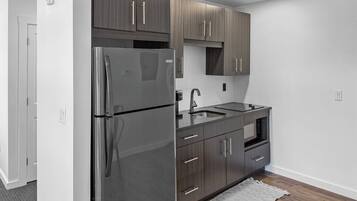 Een moderne keuken met donkere houtkasten, roestvrijstalen apparatuur en een houten vloer.