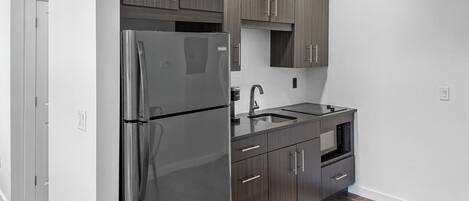 Una cocina moderna con gabinetes de madera oscura, electrodomésticos de acero inoxidable y piso de madera.