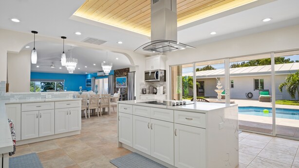 A modern kitchen with white cabinets, a central island, and a view of a swimming pool. - Villa Francisca East-Spacious 3Bedroom Retreat with A/C – Your Perfect Getaway (St Thomas)