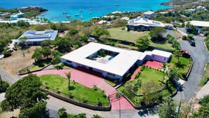 An aerial view of a coastal property with a large building featuring a central courtyard, surrounded by lush greenery and a clear view of the ocean. - Villa Francisca East-Spacious 3Bedroom Retreat with A/C – Your Perfect Getaway (St Thomas)