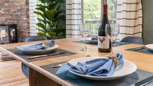 A dining table set with plates, napkins, cutlery, and a bottle of wine. - Wooded Nest, Cozy 3BR Chalet Near Spas & Hiking (Berkeley Springs)