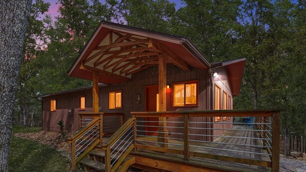 A rustic cabin with a wooden deck and stairs leading to the entrance. - Wooded Nest, Cozy 3BR Chalet Near Spas & Hiking (Berkeley Springs)