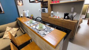 Een kleine keuken met een centraal kookeiland, houten kastjes en een magnetron.