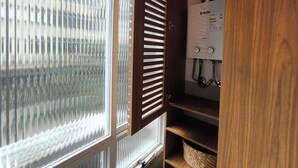 Een badkamer met een raam, een houten deur en een inbouwboiler.