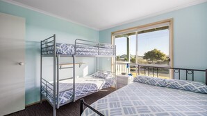 Une chambre de dortoir avec des lits superposés, un petit bureau et une fenêtre donnant sur un paysage agréable.