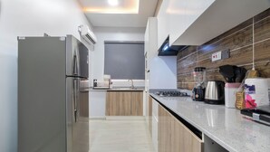 Une cuisine moderne dotée d’un réfrigérateur en acier inoxydable, de meubles en bois, d’un plan de travail en granit et d’un four encastré.