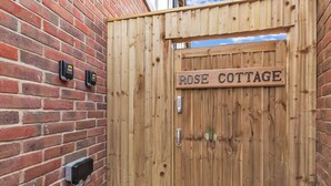 A wooden gate with a sign reading "ROSE COTTAGE" and a keyhole lock. - Garden Lodge With Parking  | By My Getaways (Brighton)