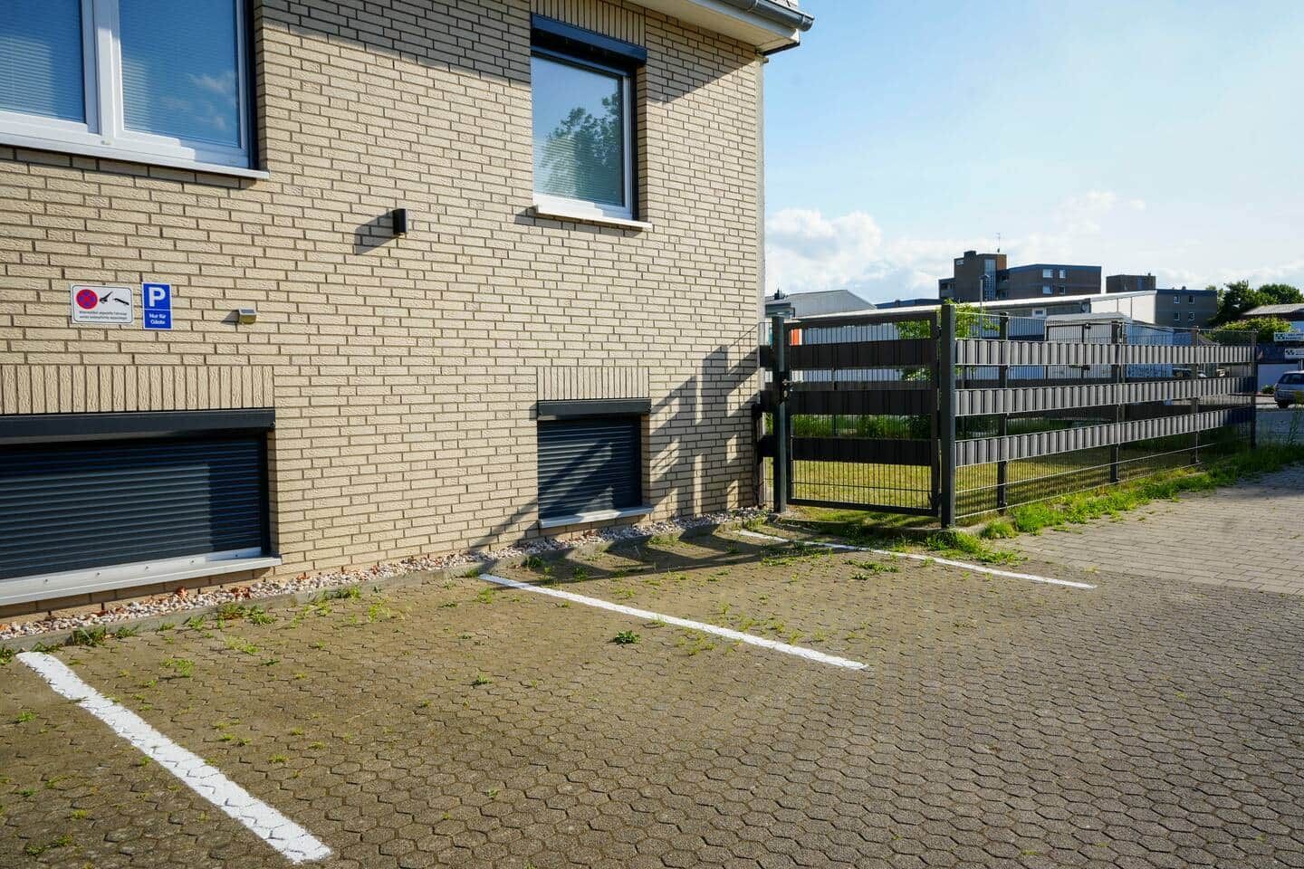 Un bâtiment à la façade en briques, doté d’un parking sécurisé et d’un chemin piétonnier dallé.