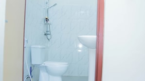Un baño pequeño con inodoro, lavamanos y ducha.