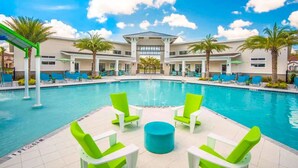 A swimming pool with green chairs and a palm tree in the background. - Beautiful Disney Home! Heated Pool/Spa • Arcade • Gated Community • 4BR / 3BA (Kissimmee)