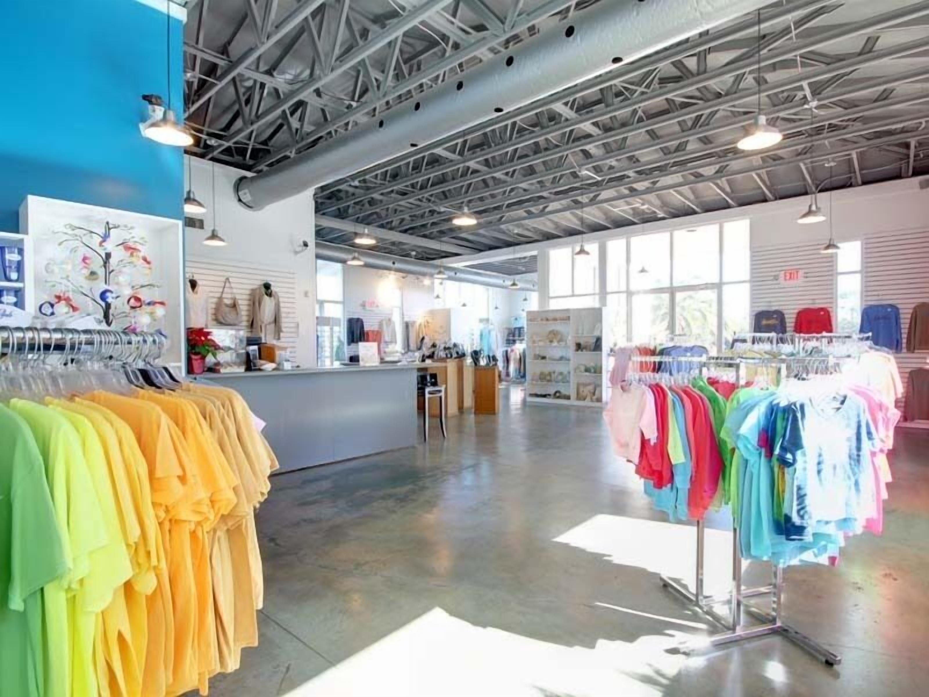 Un vaste magasin proposant une large gamme de produits, doté de hauts plafonds et de grandes fenêtres, et présentant des présentoirs à vêtements aux couleurs variées.