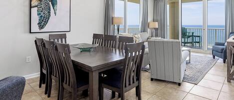 Un comedor con mesa y sillas, un sofá, un balcón con vistas y un ventilador de techo.