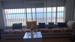 Un soggiorno con un divano rivolto verso una grande finestra con vista sulla spiaggia.