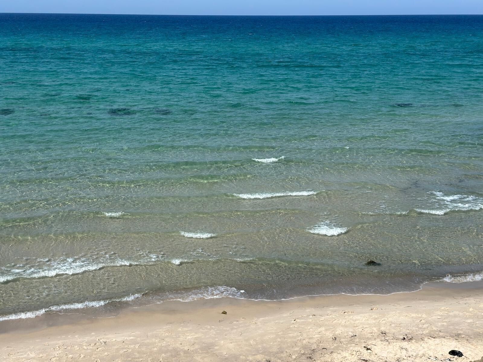 A beach with clear turquoise water and sandy shore.