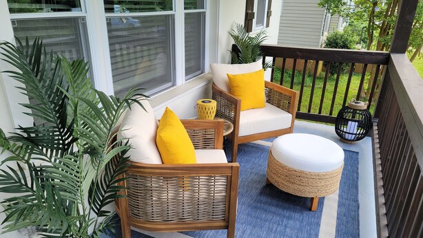 A covered porch with wicker furniture, a blue and white striped rug, and potted plants. - Wanderlust With Us (Atlanta)