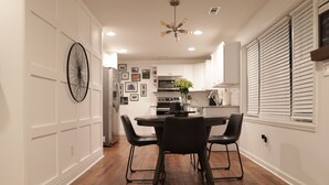 A modern kitchen with white cabinetry, a dining table with chairs, and a chandelier. - Wanderlust With Us (Atlanta)