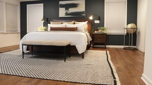 A bedroom with a large bed, bedside tables, a globe, and a painting on the wall. - Wanderlust With Us (Atlanta)