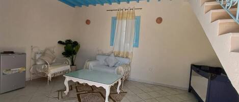 A living room with a blue ceiling, a sofa set, a coffee table, a staircase, and a small table with a plant.