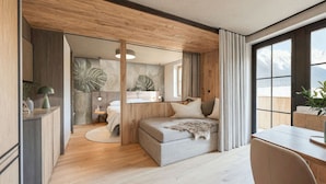 Ein gemütliches Schlafzimmer mit Bett, Schreibtisch und Blick auf schneebedeckte Berge.