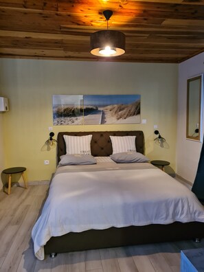 A bedroom with a large bed, two bedside tables, a ceiling fan, and a wall-mounted lamp. - Les chambres et table d'hôte du voyageur / CHAMBRE VERVEINE (La Plaine-des-Palmistes)