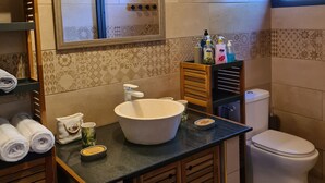 A bathroom with a large sink, a mirror, a toilet, and a window.