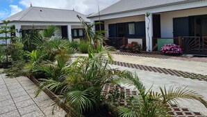 A two-story building with a tiled roof and a garden area with various plants and flowers.