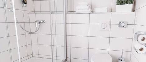 Un baño moderno con cabina de ducha de vidrio, inodoro y lavabo.