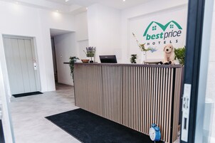 Una recepción con el logotipo de 'best price hotels' y un peluche en la barra.