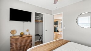 Quarto com uma cama, cômoda, televisão e armário.