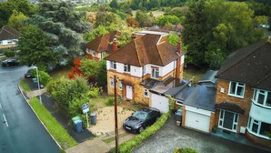 A two-story house with a garage, surrounded by greenery and a view of a town in the distance.
