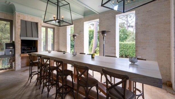Una cocina moderna con una isla grande, sillas de madera oscura e iluminación colgante.