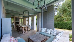 Un patio techado con zona de comedor, sofá y mesa.