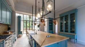 Una cocina amplia con una isla grande, armarios azules e iluminación colgante.
