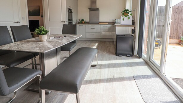 Una cocina moderna con comedor, que incluye una mesa de mármol, sillas negras y un banco.
