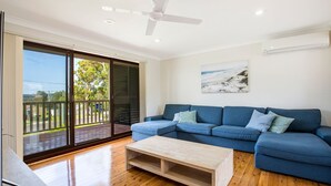 A modern living room with a blue sofa, a wooden coffee table, and a ceiling fan.