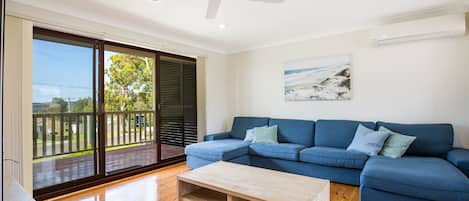 Una sala de estar moderna con un sofá azul, una mesa de centro de madera y un ventilador de techo.