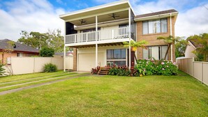 A two-story house with a balcony, a garage, and a well-maintained lawn.