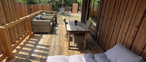 A wooden deck with a sofa, a table, and a chair.