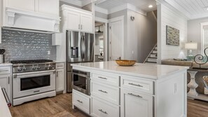 Una cucina moderna con mobili bianchi, elettrodomestici in acciaio inossidabile e una grande isola.