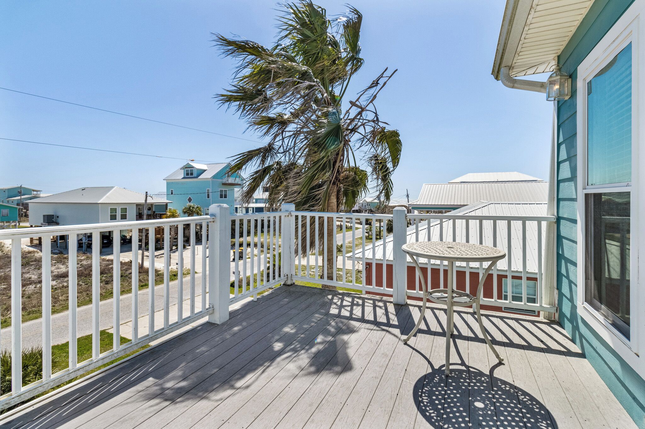 A wooden deck with a white railing, a small table, and a chair.