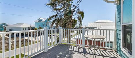 A wooden deck with a white railing, a small table, and a chair.