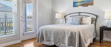 Ein Schlafzimmer mit einem Bett, zwei Nachttischen, einem Fenster mit Jalousien und einem Bild an der Wand.