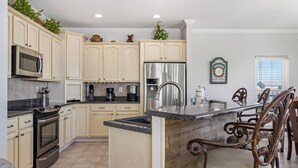 A modern kitchen with cream cabinets, stainless steel appliances, and a wooden island. - Beach Memories by Southern Vacation Rentals (Gulf Shores)