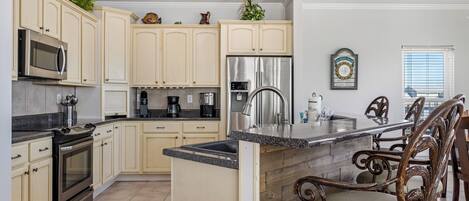 A modern kitchen with cream cabinets, stainless steel appliances, and a wooden island.