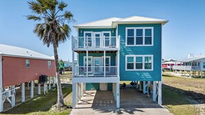 A two-story building with a balcony, a concrete walkway, and a palm tree. - Beach Memories by Southern Vacation Rentals (Gulf Shores)