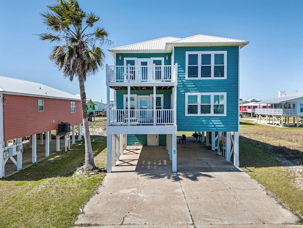 A two-story building with a balcony, a concrete walkway, and a palm tree. - Beach Memories by Southern Vacation Rentals (Gulf Shores)