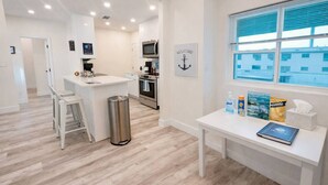 A modern kitchen with a central island, stainless steel appliances, and a window with a view. - Blue Wave Retreat (Beach) (Daytona Beach)