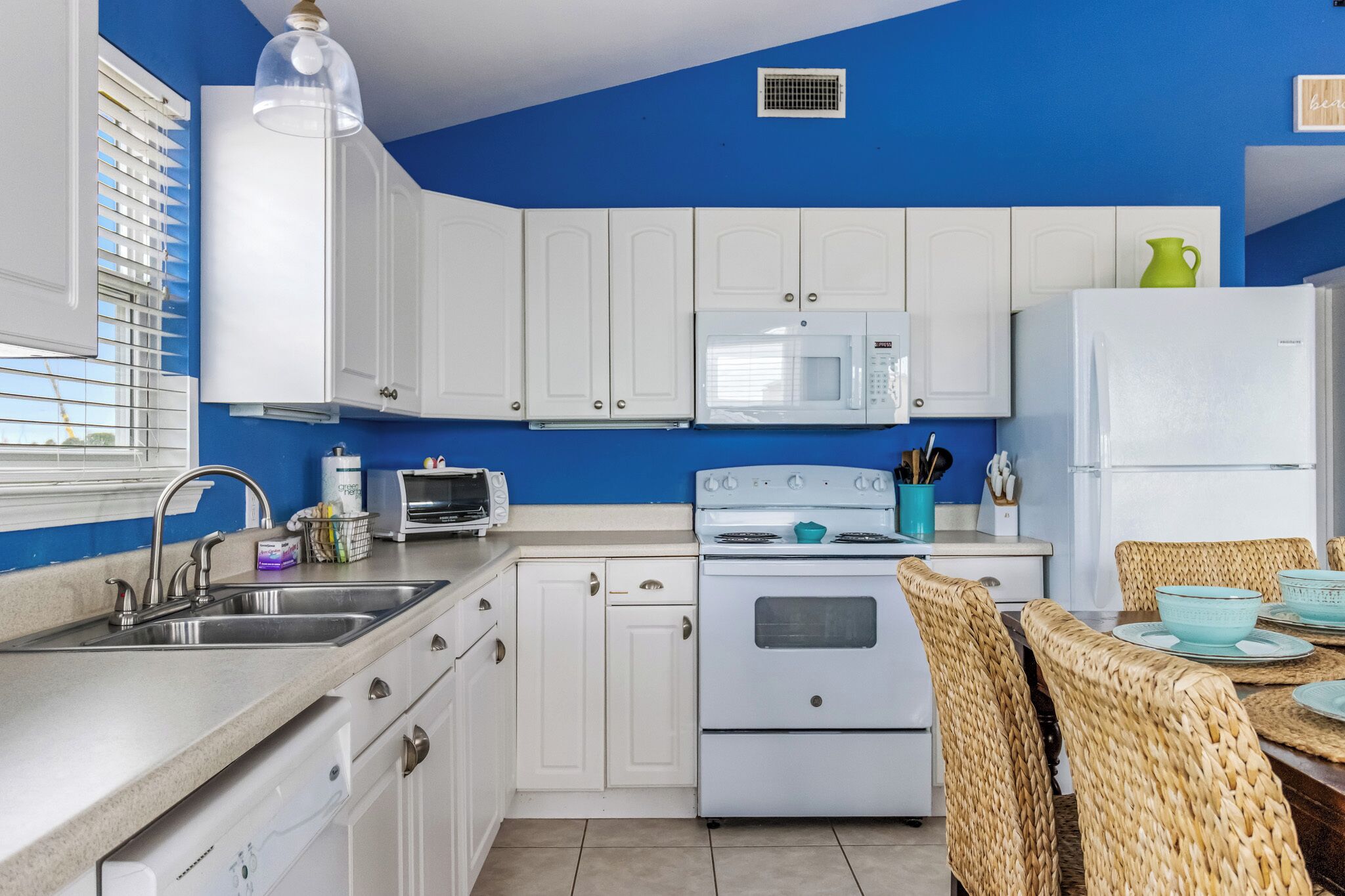 A kitchen with white cabinets, a microwave, a stove, and a sink.
