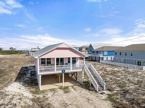 Une maison située en bord de mer, dotée d’un balcon et d’un escalier menant au bâtiment principal.