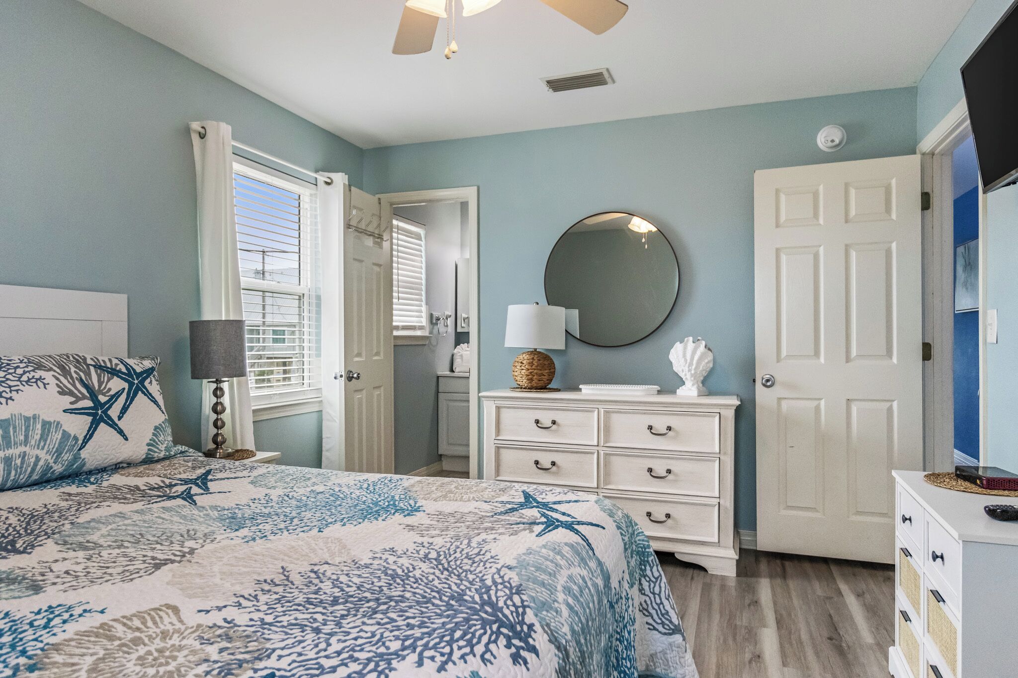 A bedroom with a bed, a dresser, a mirror, and a door.
